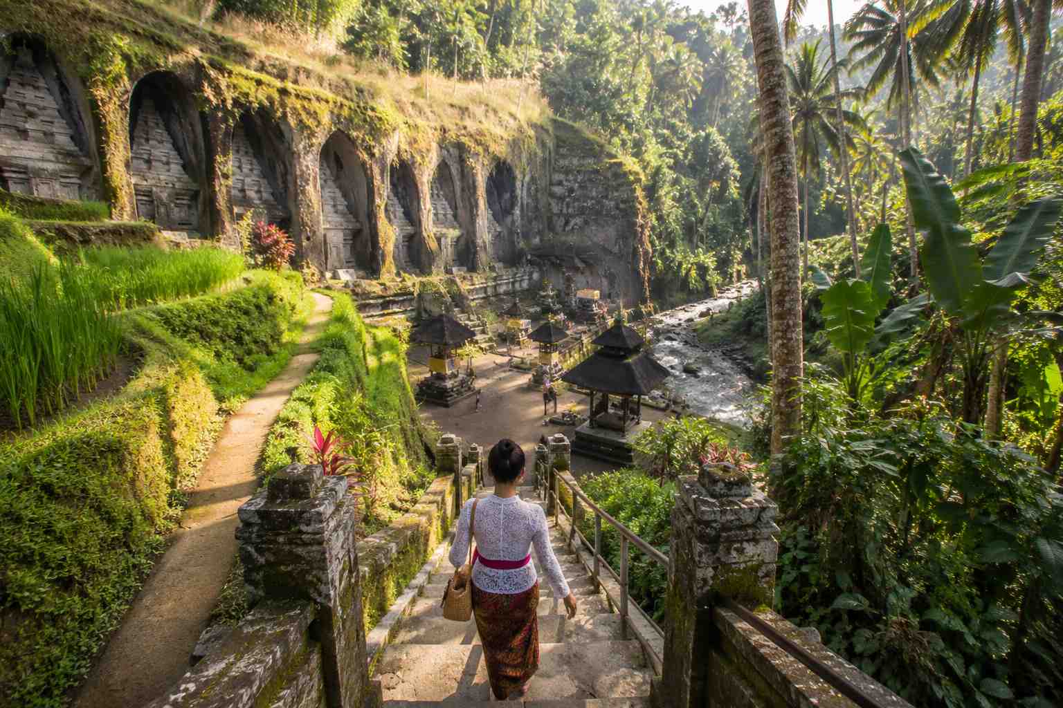 Ancient Gunung Kawi Temple carved into cliffs in Ubud Bali with tropical jungle and flowing river