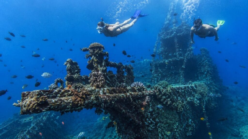 Amed snorkeling tour guide leading beginners to explore colorful coral reefs at Jemeluk Bay in East Bali.